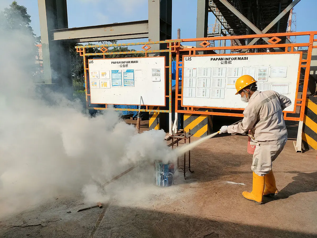 Worker using a fire extinguisher during a site safety drill